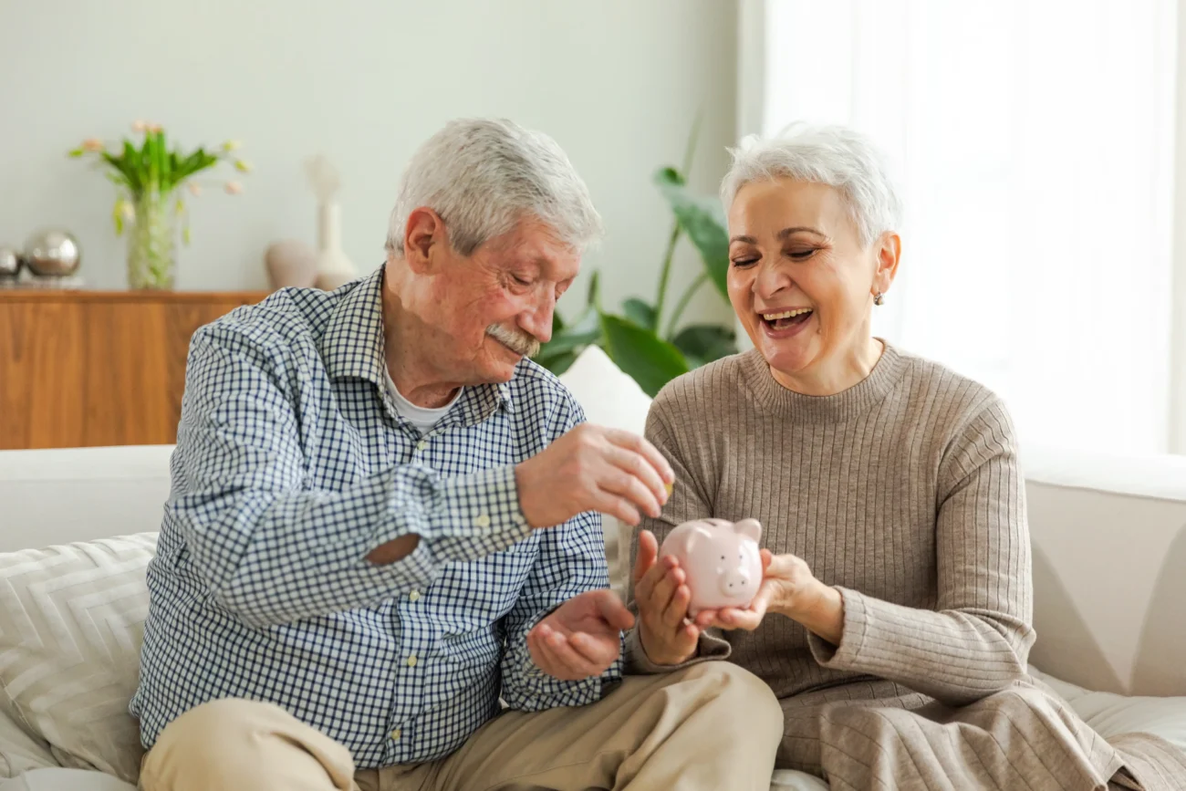O peníze je potřeba pečovat v každém věku. Zdroj: Shutterstock | TVGURU.cz Senioři dávající peníze do kasičky.