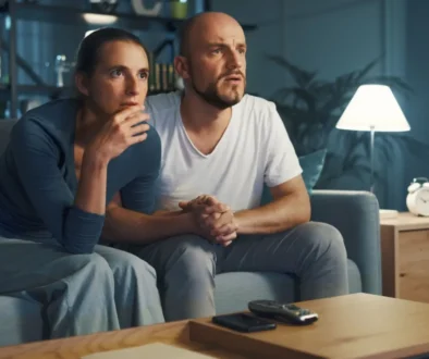 pár na gauči sleduje televizi s překvapeným výrazem