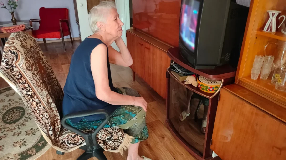 Babička se kouká na starou televizi.