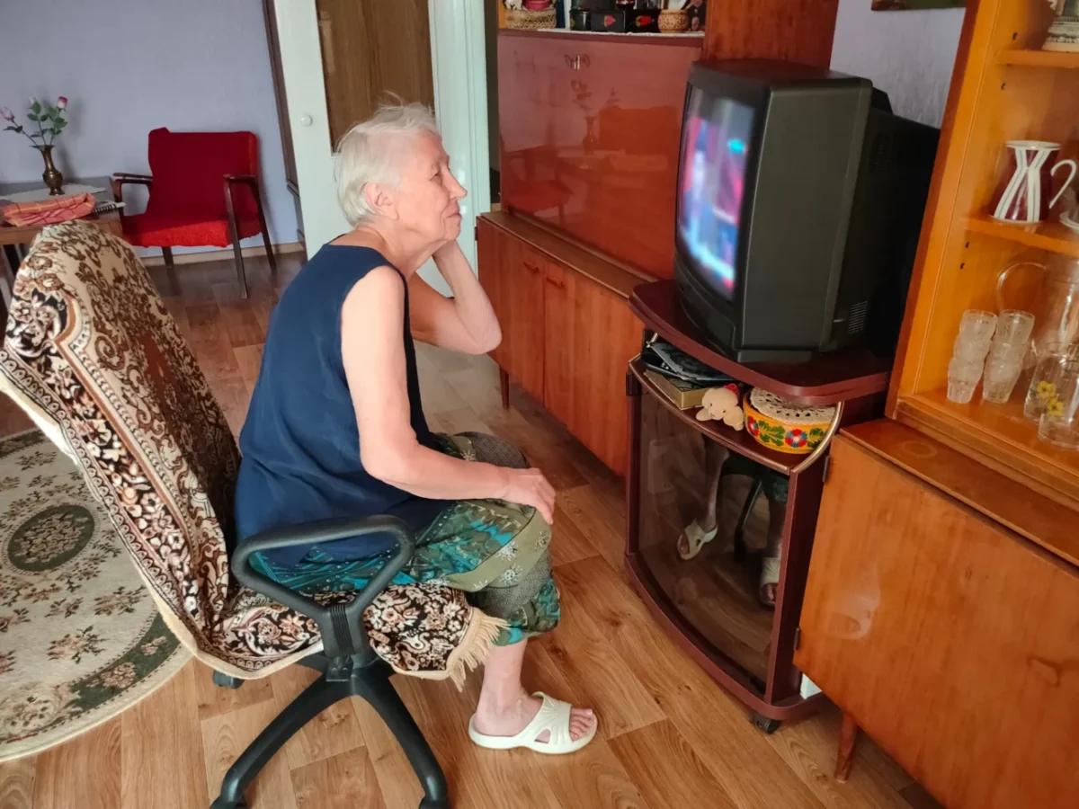 Babička se kouká na starou televizi.