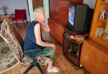 Babička se kouká na starou televizi.