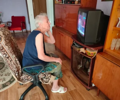 Babička se kouká na starou televizi.
