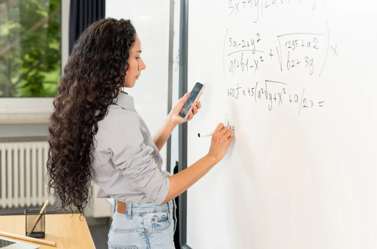 Žena u tabule počítá složitý příklad.