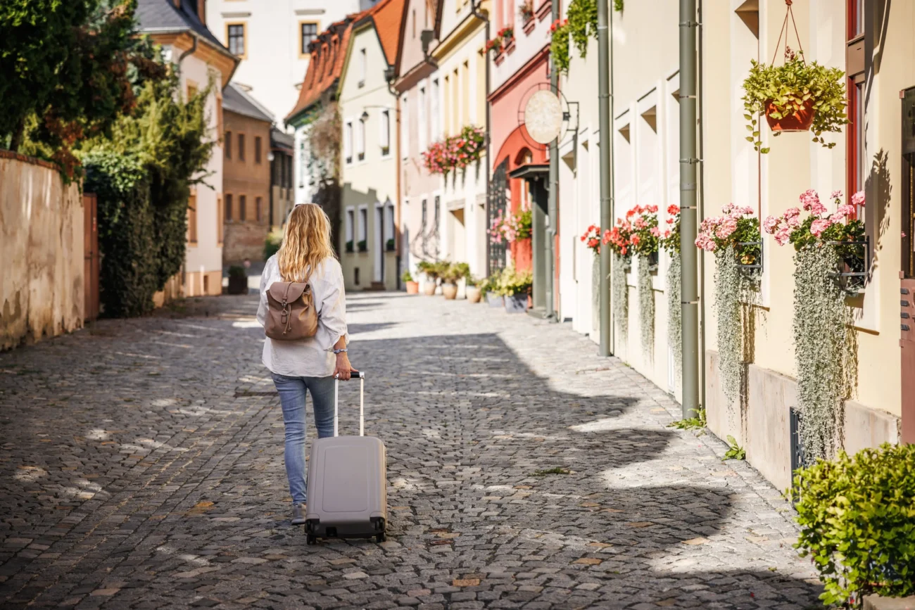 I Češi by občas měli více cestovat po našich městech. Zdroj: Shutterstock | TVGURU.cz Žena s kufrem v českých uličkách.