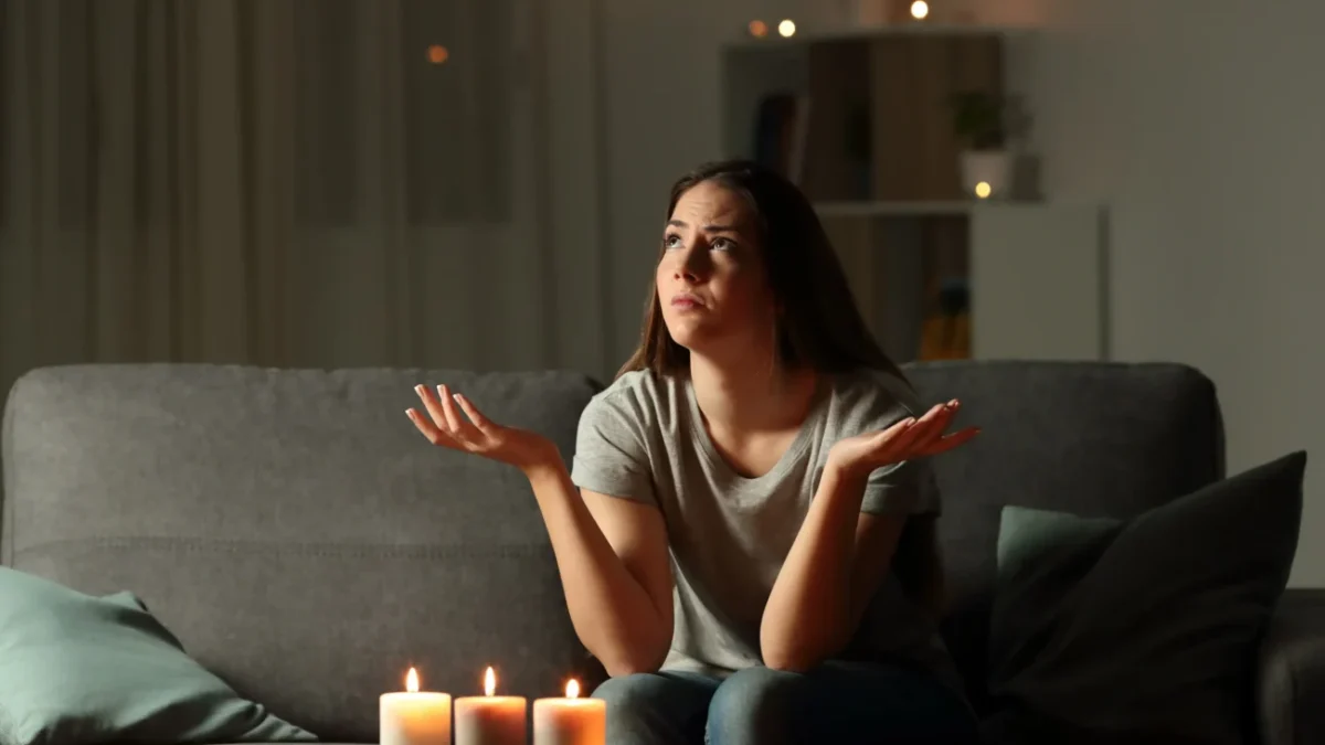Žena sedí při svíčkách, protože je bez proudu.
