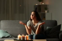 Žena sedí při svíčkách, protože je bez proudu.