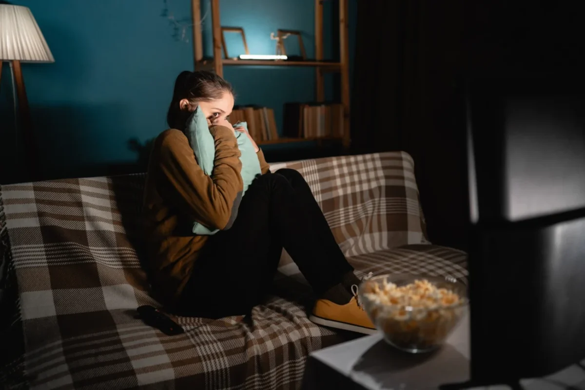 Žena sleduje hororový film.