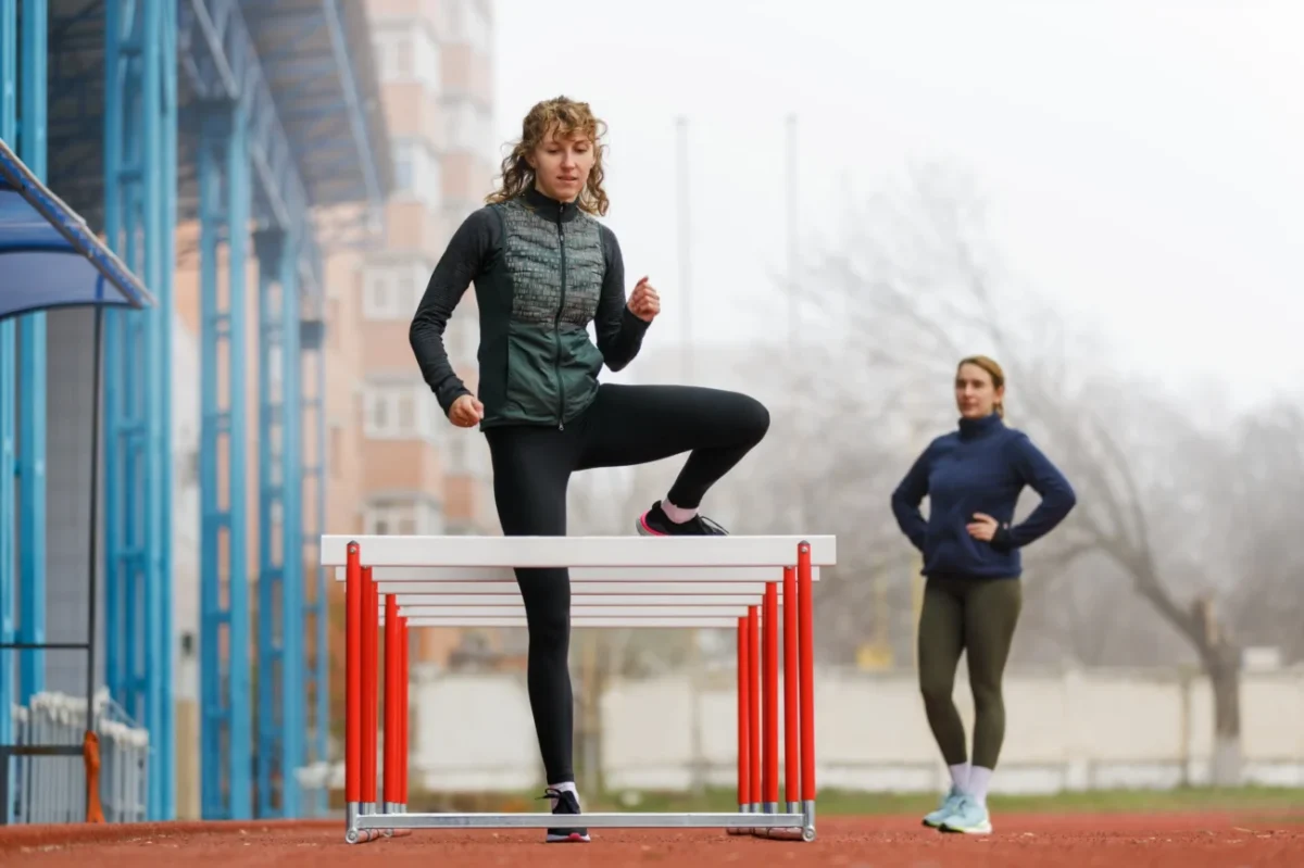 Žena se snaží překonat překážky na dráze.