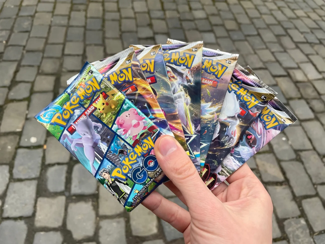 shutterstock_2265832897-2 | TVGURU.cz Člověk v ruce drží zabalené Pokémon kartičky.