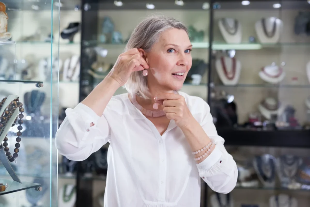 Starší žena si v obchodě zkouší náušnice.