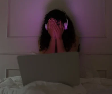 Žena sedí u notebooku a vystrašeně si zakrývá oči.