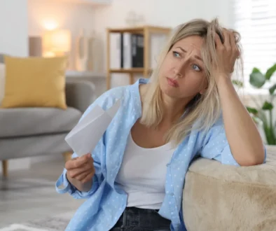 Žena sedící u gauče podpírající si hlavu.