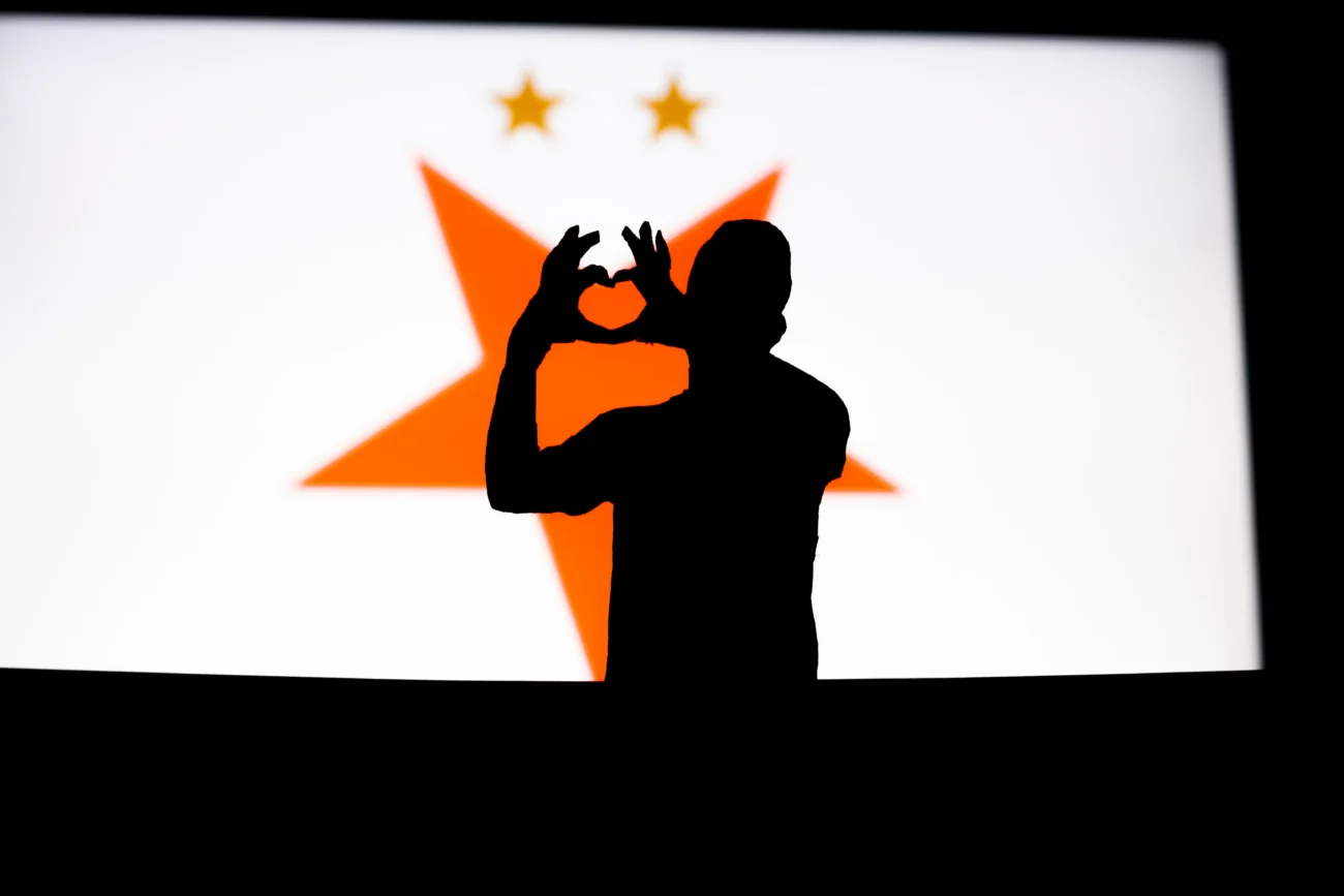 shutterstock_2272834163 | TVGURU.cz Muž stojí před logem Slavia.