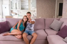 Muž a žena jsou na gauči a koukají společně na televizi.