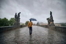 muž jde v dešti přes most