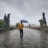 muž jde v dešti přes most