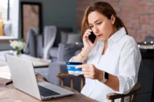 Žena telefonuje, dívá se do notebooku a opisuje údaje z karty.