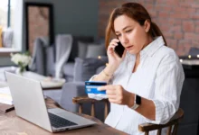 Žena telefonuje, dívá se do notebooku a opisuje údaje z karty.