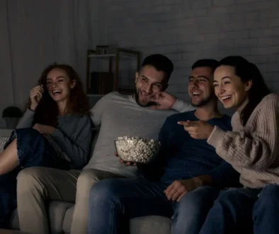 skupina mladých lidí pobaveně sleduje televizi