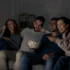 skupina mladých lidí pobaveně sleduje televizi