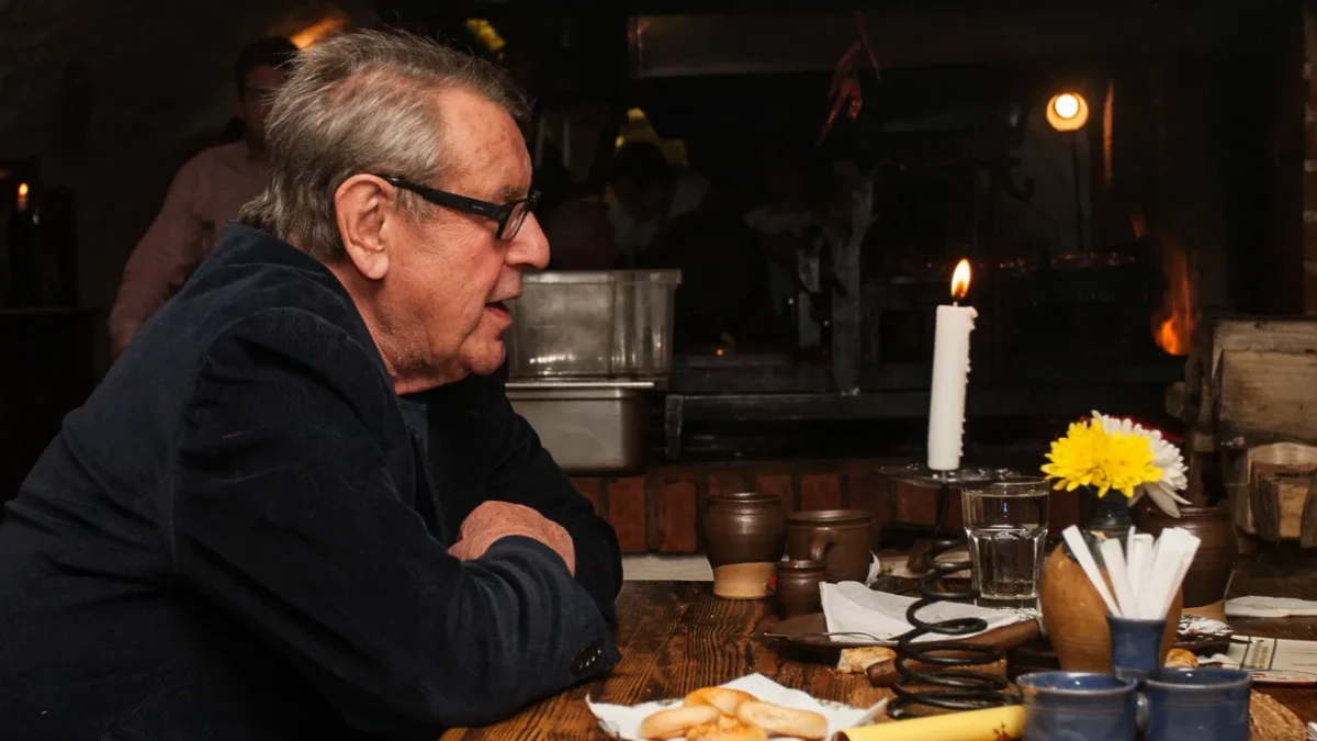 Miloš Forman sedí u stolu.