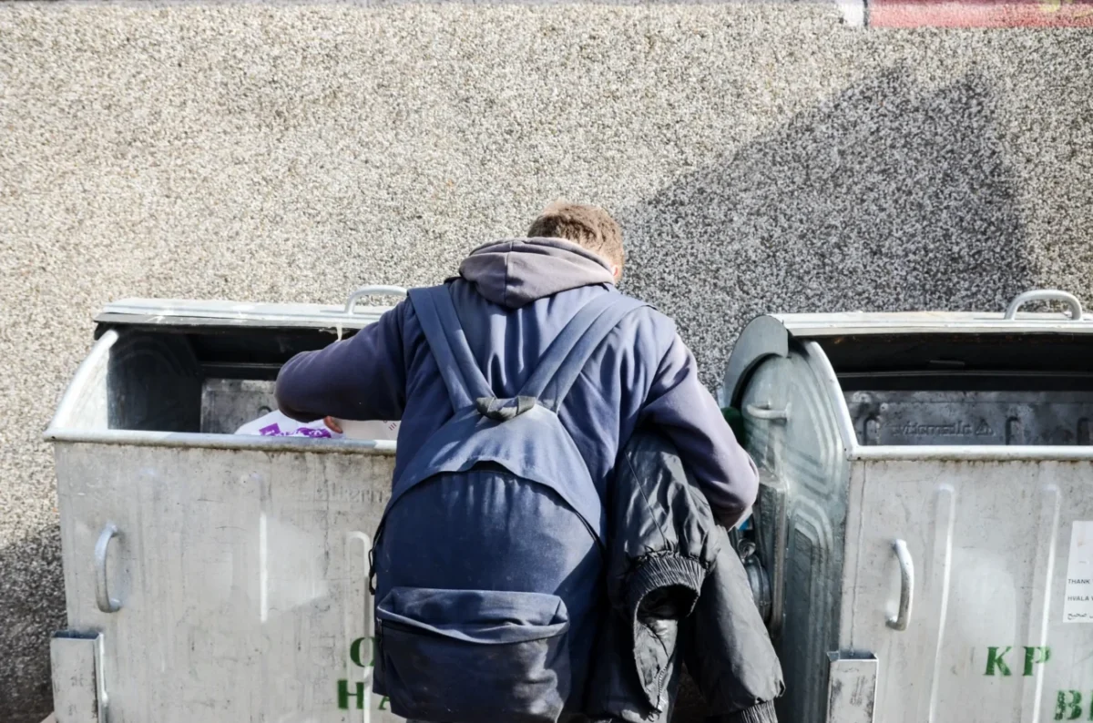 Muž prohlédává popelnice.