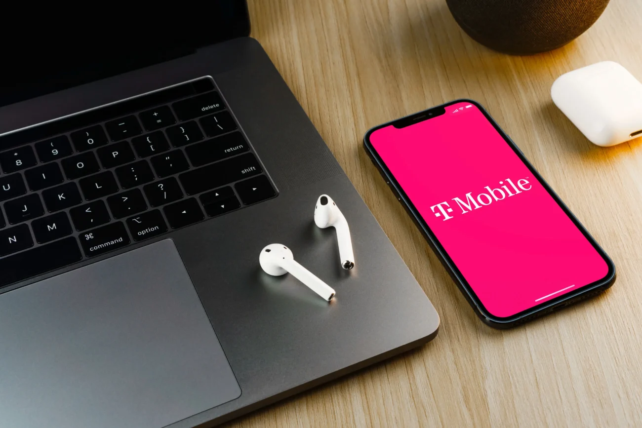 T-mobile aplikace spuštěná na telefonu a notebook se sluchátky.