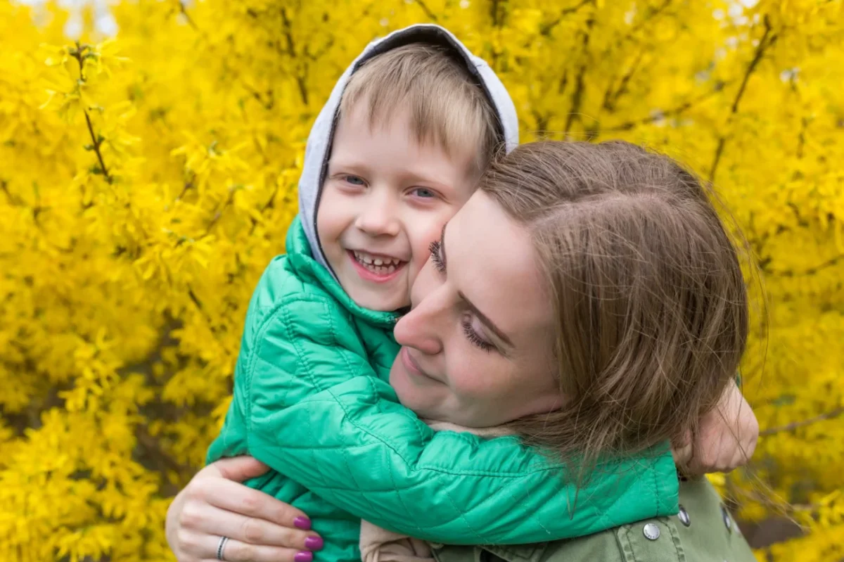 Žena v rukách drží chlapce a smějí se.