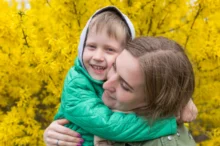 Žena v rukách drží chlapce a smějí se.