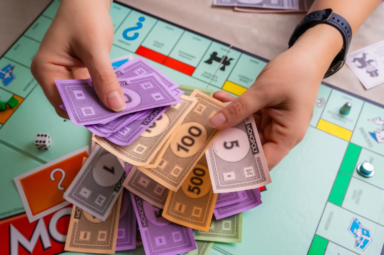 shutterstock_2586083437-2 | TVGURU.cz Člověk počítá Monopoly peníze.