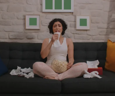 Žena je obklopená posmrkanými kapesníčky a brečí u televize.