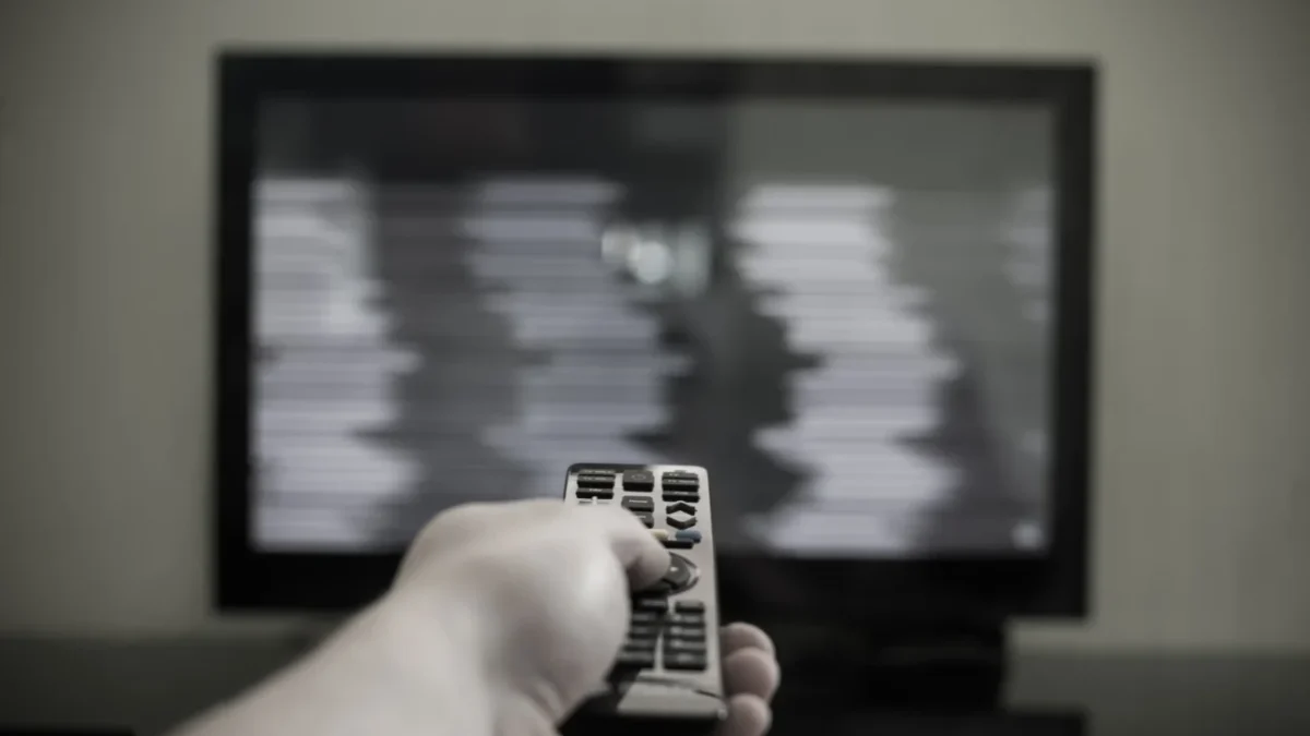 Člověk ovladačem míří na černou obrazovku.