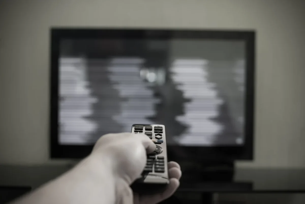 Člověk ovladačem míří na černou obrazovku.