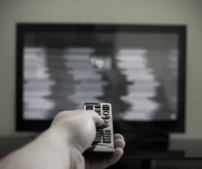 Člověk ovladačem míří na černou obrazovku.