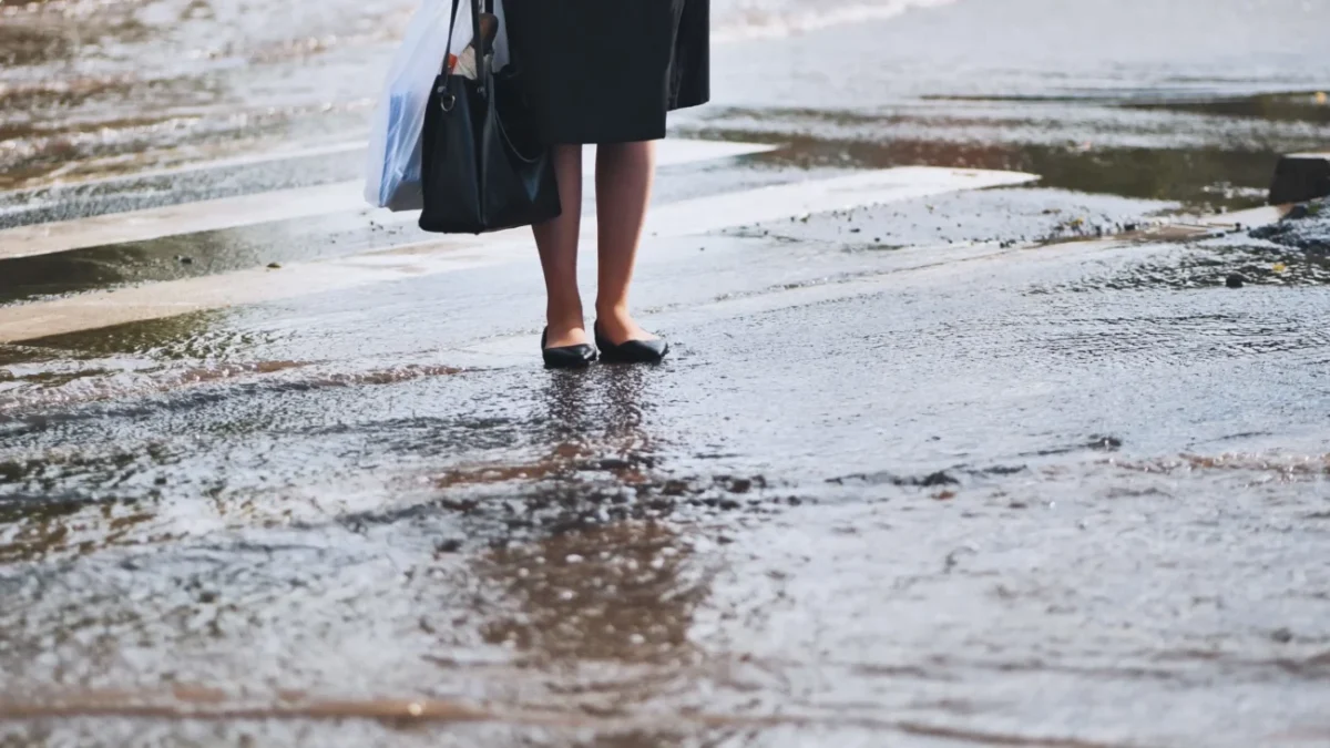 žena stojící na přechodu během vydatného deště