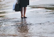 žena stojící na přechodu během vydatného deště