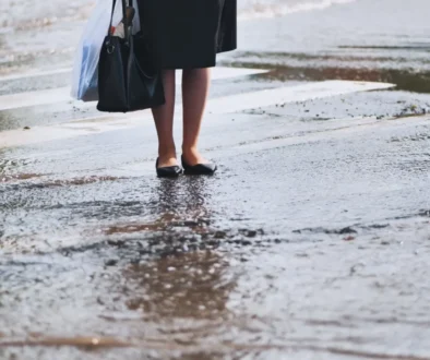 žena stojící na přechodu během vydatného deště