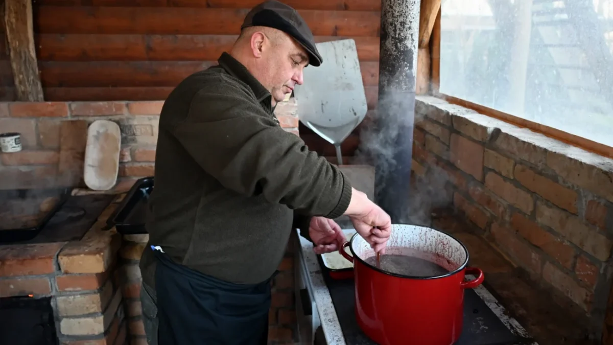 Muž vařící jídlo při zabijačce.