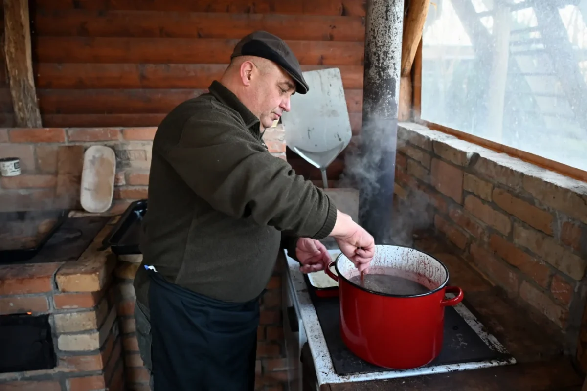 Muž vařící jídlo při zabijačce.