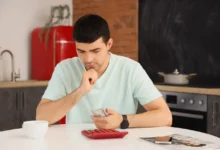 muž sedící u stolu počítající peníze