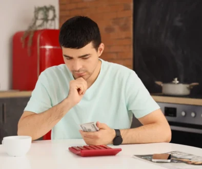 muž sedící u stolu počítající peníze