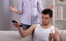 Muž v ruce drží lahev a kouká se na TV.