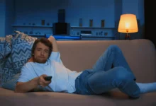 Nudící se muž dívající se na televizi.