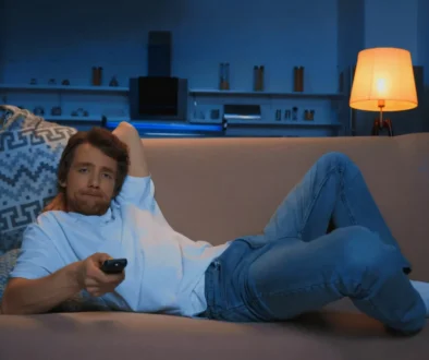 Nudící se muž dívající se na televizi.