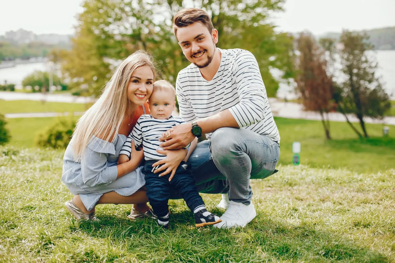 shutterstock_1630418704-2 | TVGURU.cz Mladá rodinka s miminkem pózují venku na fotku.