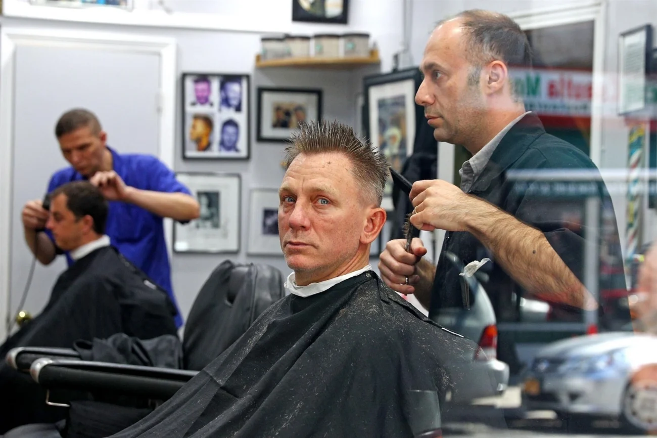 profimedia-0369818832 | TVGURU.cz Daniel Craig upravován na křesle v barber shopu.