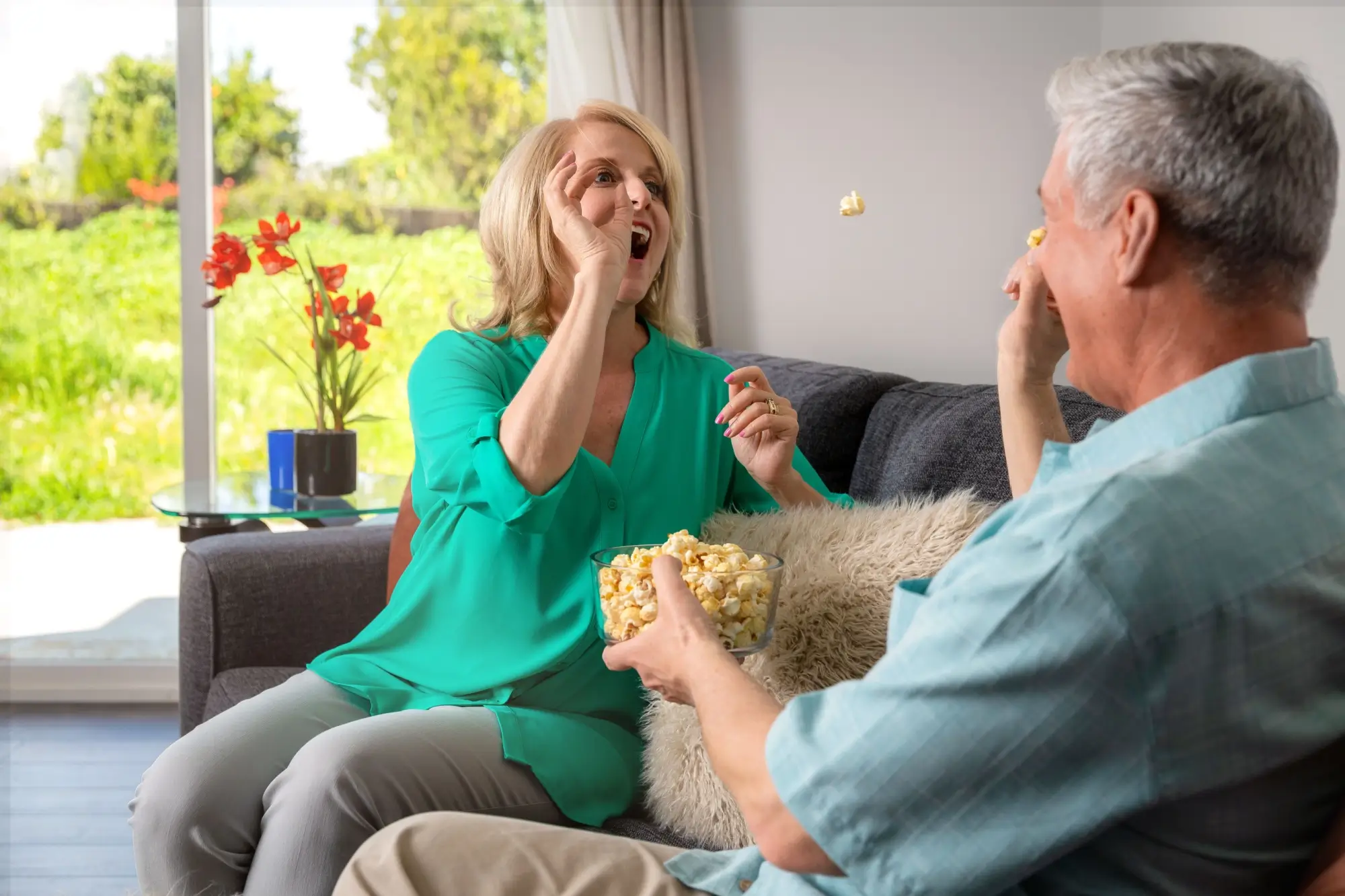 Shutterstock_1456549961 | TVGURU.cz starý pár si hraje s popcornem na gauči