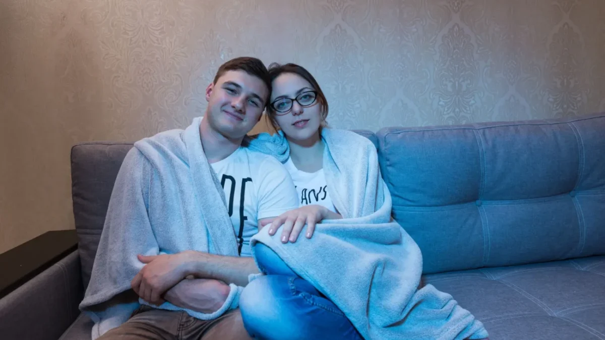 pár se tulí na gauči osvětlený obrazovkou televize