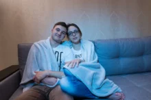 pár se tulí na gauči osvětlený obrazovkou televize