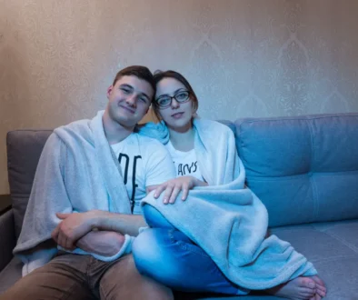 pár se tulí na gauči osvětlený obrazovkou televize